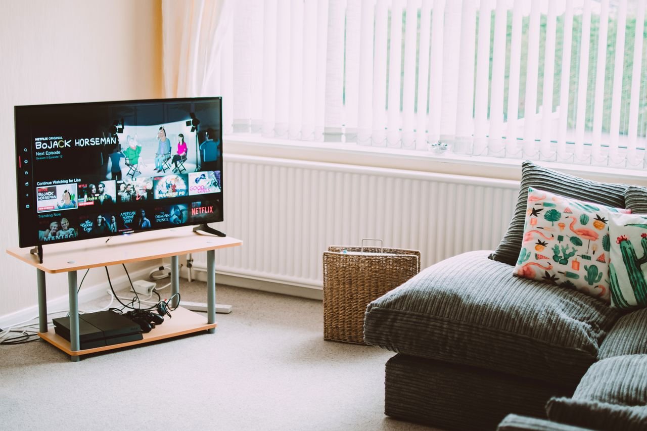 About Chic and comfortable living room featuring a modern sofa, decorative pillows, and a TV streaming popular shows.