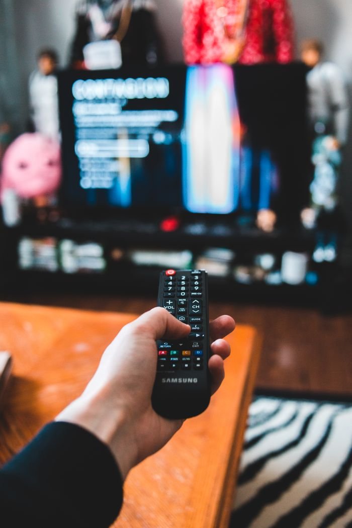 Home Person using a Samsung remote control in a living room setting for a relaxed movie night experience.