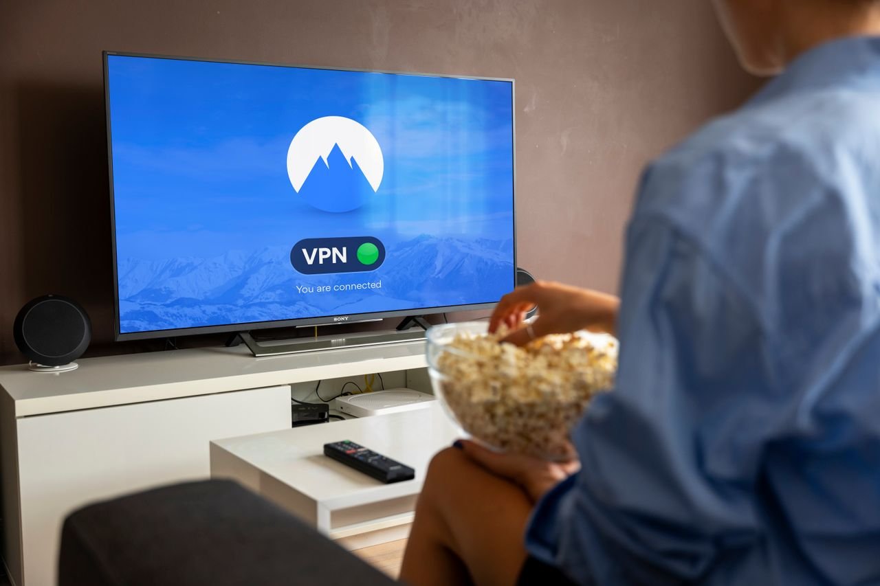 Services A relaxed scene at home with a person enjoying popcorn while watching a VPN-protected TV.