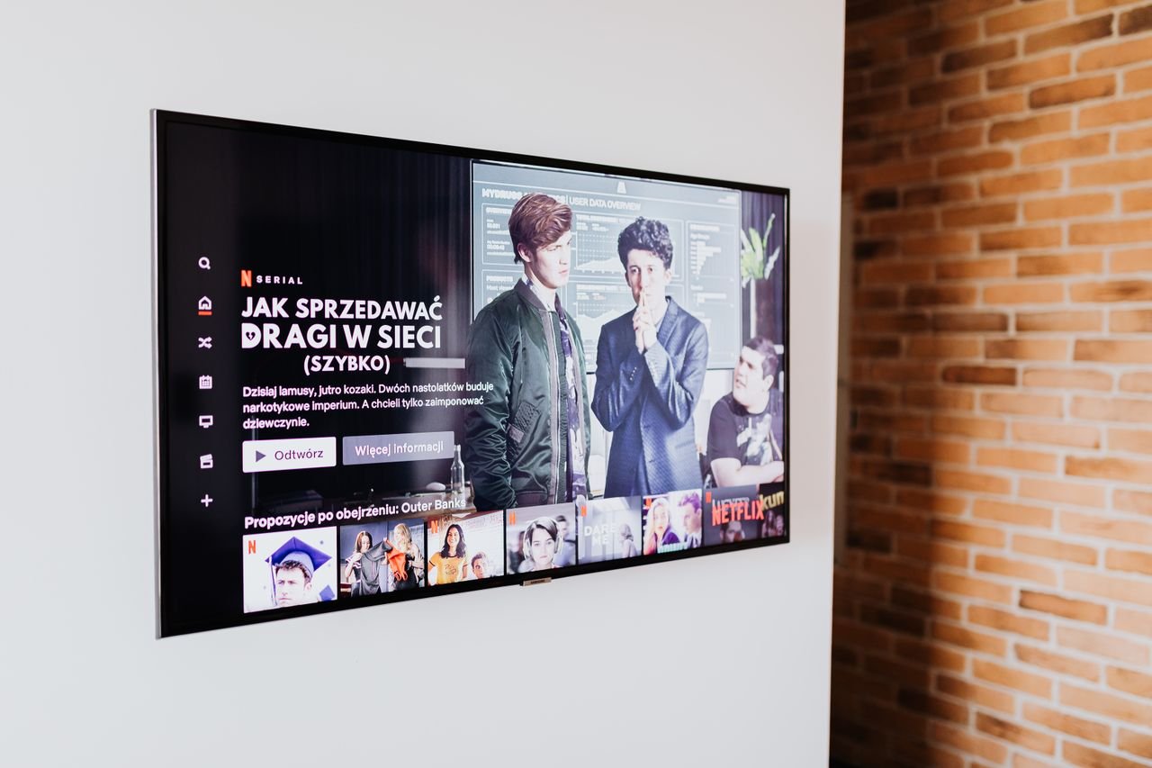 Services Smart TV displaying streaming content in modern living room setting with exposed brick wall.