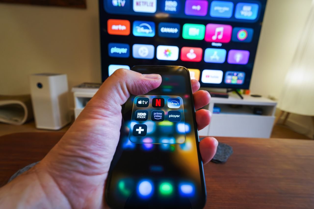 The Art of Drawing Readers In: Your attractive post title goes here Close-up of a hand holding a phone displaying streaming apps in front of a TV with multiple app icons.